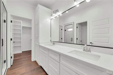 Full bathroom featuring a walk in closet, wood finished floors, a sink, and a stall shower