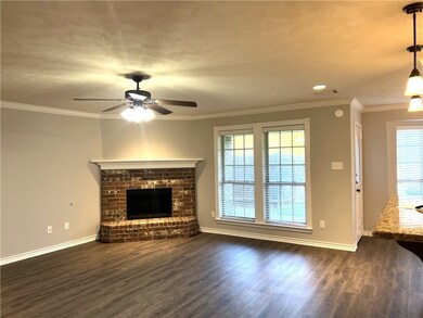 Unfurnished living room with ceiling fan, a fireplace, dark wood-type flooring, and ornamental molding