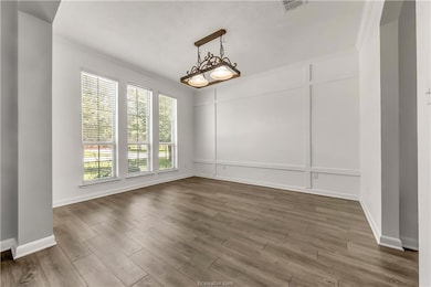Unfurnished dining area featuring ornamental molding, wood finished floors, and a decorative wall