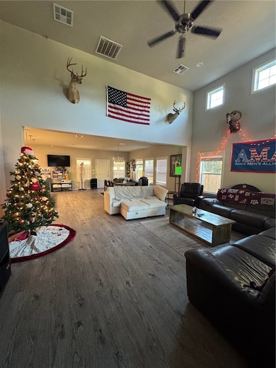 Living area featuring a towering ceiling, wood finished floors, and a ceiling fan