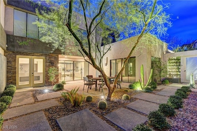 Rear view of house with stucco siding, stone siding, french doors, and a patio