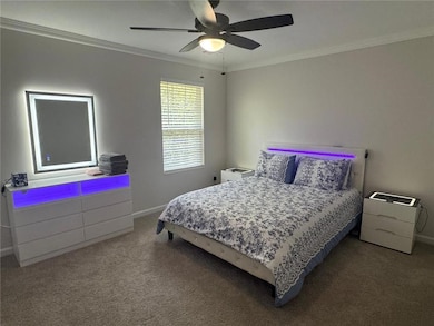 Bedroom with crown molding, carpet floors, and ceiling fan