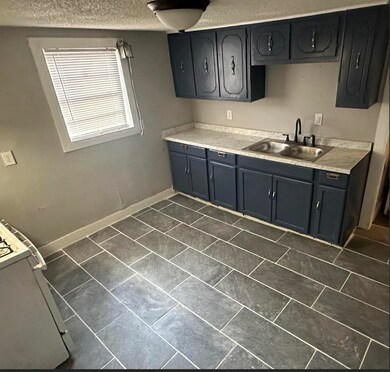 Kitchen featuring a textured ceiling, white range, and sink