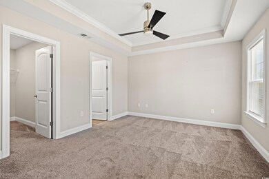 Unfurnished bedroom featuring a tray ceiling, carp