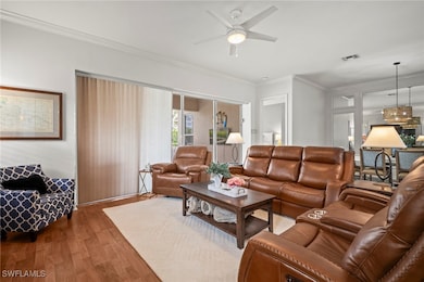 Living area featuring ornamental molding, wood finished floors, a chandelier, and ceiling fan