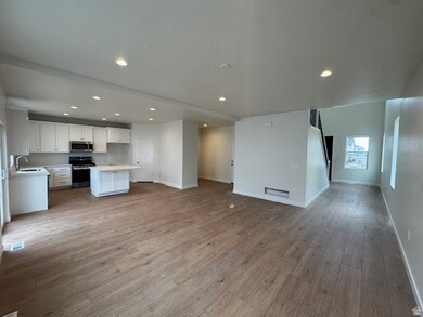 Kitchen featuring open floor plan, light countertops, white cabinets, appliances with stainless steel finishes, and a center island