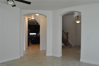 Spare room with arched walkways, a ceiling fan, stairs, and light tile patterned floors