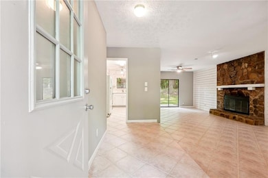 Foyer with a fireplace, a textured ceiling, light tile patterned floors, and ceiling fan