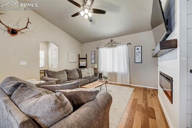 Living room featuring vaulted ceiling, ceiling fan
