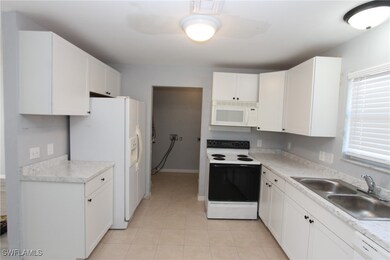 Kitchen with white cabinetry, white appliances, li