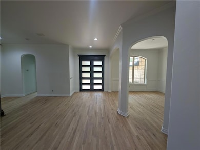 Foyer entrance featuring arched walkways, crown molding, wood finished floors, and recessed lighting