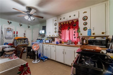 Kitchen with gas range oven, stainless steel microwave, white cabinets, and a sink