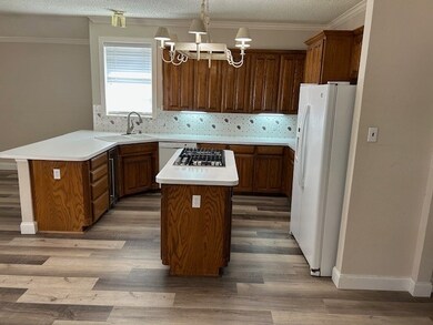 Kitchen with crown molding, sink, a kitchen island, and white fridge with ice dispenser