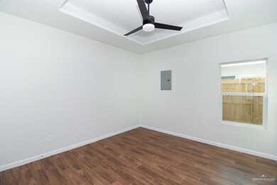 Empty room featuring ceiling fan, dark hardwood / wood-style flooring, electric panel, and a tray ceiling
