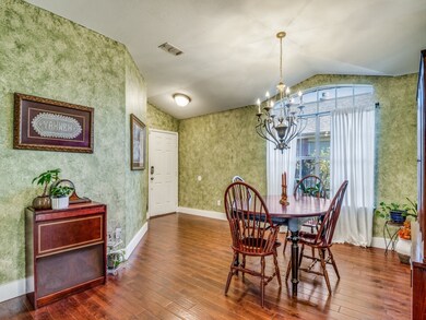 Dining space with a chandelier, wallpapered walls, wood-type flooring, and lofted ceiling