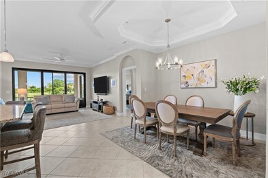 Dining area with arched walkways, ornamental molding, light tile patterned floors, a chandelier, and a raised ceiling