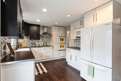 Kitchen with white appliances, wall chimney exhaust hood, tasteful backsplash. All appliances stay