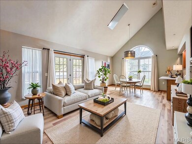 Digitally Staged Living room with high vaulted ceiling, light wood-style flooring, a skylight, and french doors