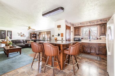 Kitchen with white refrigerator, a kitchen bar, ceiling fan, a textured ceiling, and tile floors