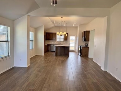 Kitchen with light countertops, lofted ceiling, appliances with stainless steel finishes, decorative backsplash, and dark brown cabinets