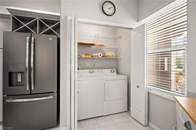 Laundry area featuring separate washer and dryer, light tile patterned floors, and baseboards