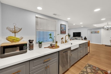 Kitchen featuring gray cabinetry, dishwasher, black microwave, light wood finished floors, and recessed lighting