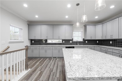 Kitchen with gray cabinetry, light stone countertops, hanging light fixtures, light wood finished floors, and recessed lighting