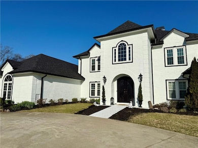 French country style house with stucco siding, a shingled roof, and a front yard