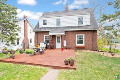 Back of house featuring brick siding, a yard, and a deck