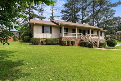 Ranch-style home featuring board and batten siding, covered porch, stairway, and brick siding