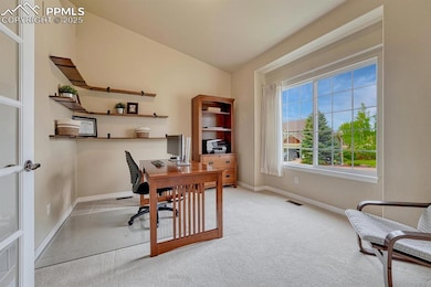 Carpeted office space featuring baseboards and vaulted ceiling