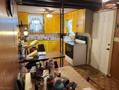 Kitchen with beam ceiling, electric range, ceiling fan, and wooden walls