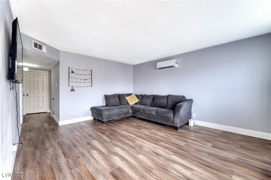Living area with an AC wall unit, wood finished fl