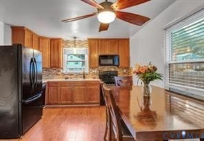 Kitchen with freestanding refrigerator, tasteful backsplash, light wood-style floors, brown cabinets, and light countertops