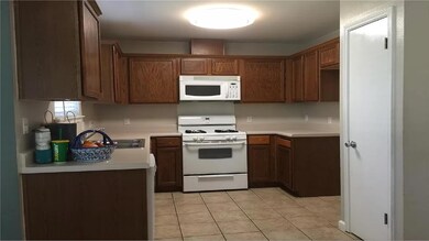 Kitchen featuring white appliances, light tile pa