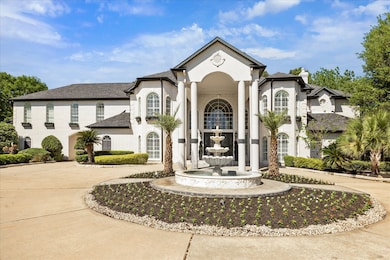 The exterior is accented with manicured landscaping and tall windows, providing a luxurious and welcoming curb appeal.