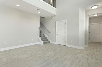 Unfurnished living room featuring stairs, light w