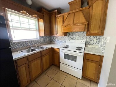 Kitchen featuring white electric stove, freestanding refrigerator, custom range hood, light tile patterned flooring, and light countertops