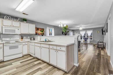 Kitchen with a peninsula, white appliances, a sink, visible vents, and light countertops