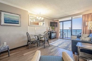 Dining area featuring wood finished floors, crown molding, a textured ceiling, and an inviting chandelier