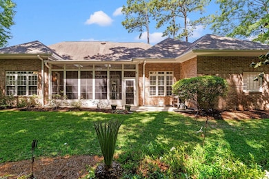 Rear view of house featuring brick siding, a lawn, a sunroom, and a shingled roof