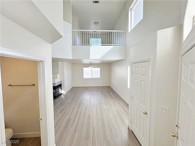 Unfurnished living room with a high ceiling, light wood-style flooring, healthy amount of natural light, and a fireplace