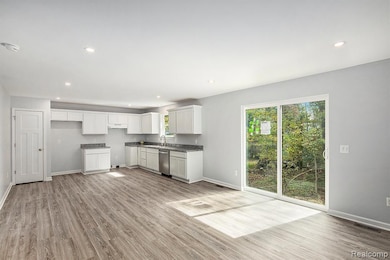 Kitchen with recessed lighting, light wood-type flooring, white cabinetry, and stainless steel dishwasher