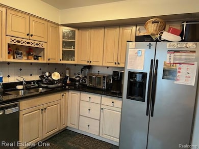 Kitchen with stainless steel refrigerator with ice dispenser, backsplash, dishwasher, glass insert cabinets, and dark stone counters