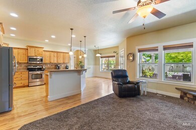 Kitchen with appliances with stainless steel finishes, a breakfast bar area, open floor plan, light wood finished floors, and tasteful backsplash