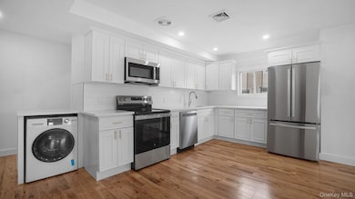 Kitchen featuring visible vents, light countertops, washer / dryer, appliances with stainless steel finishes, and light wood-style floors