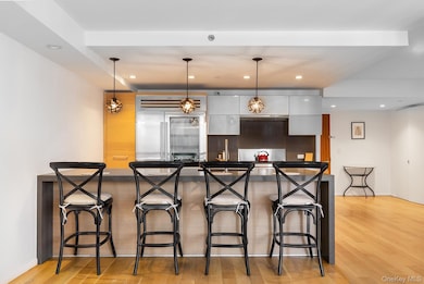 Kitchen with pendant lighting, recessed lighting, light wood-style flooring, built in refrigerator, and a breakfast bar
