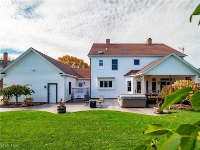 Rear view of property with a hot tub, a yard, a patio area, and a chimney