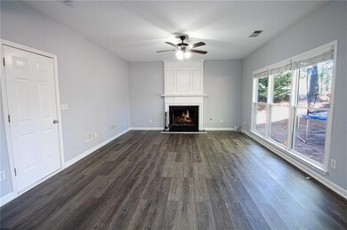 Unfurnished living room featuring dark wood finished floors, a ceiling fan, and a large fireplace