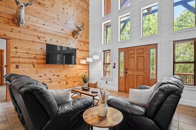 Tiled living area featuring plenty of natural light, a high ceiling, wooden walls, and baseboards
